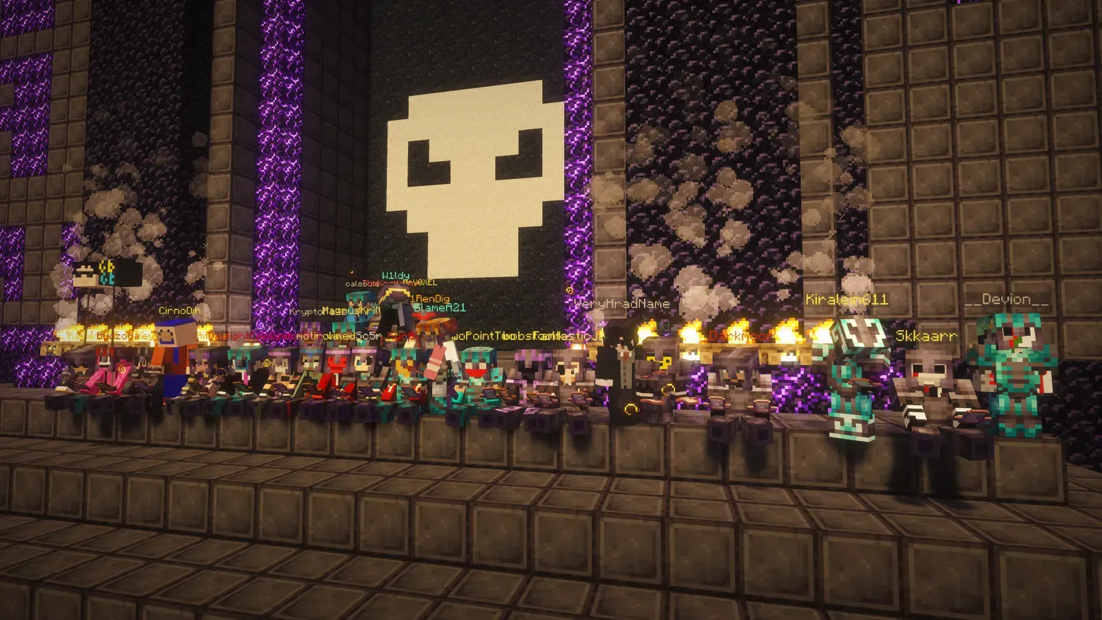 A row of players in costumes lined up on a ledge under a giant pixel-art skull at the entrance of the Halloween maze